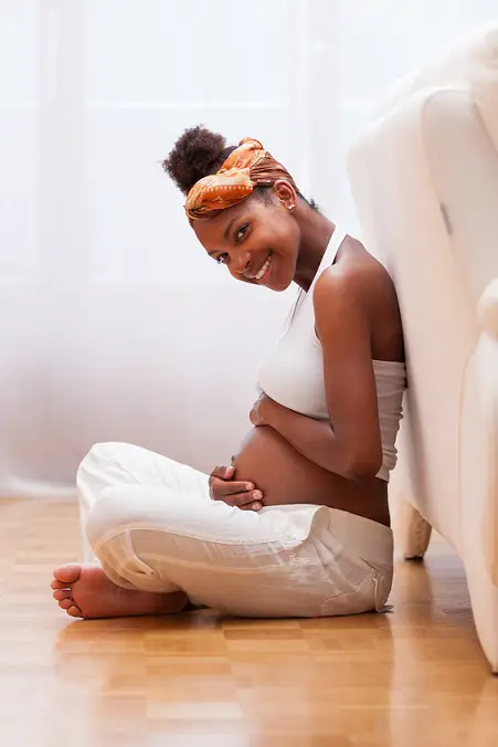 Young pregnant black woman touching her belly - African people