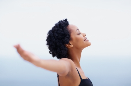 Happy and healthy black young woman relaxing with open arms outdoors